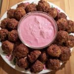 A round white plate with Turkey Meatballs with Blue Cheese Horseradish in the center in a clear round dip bowl.