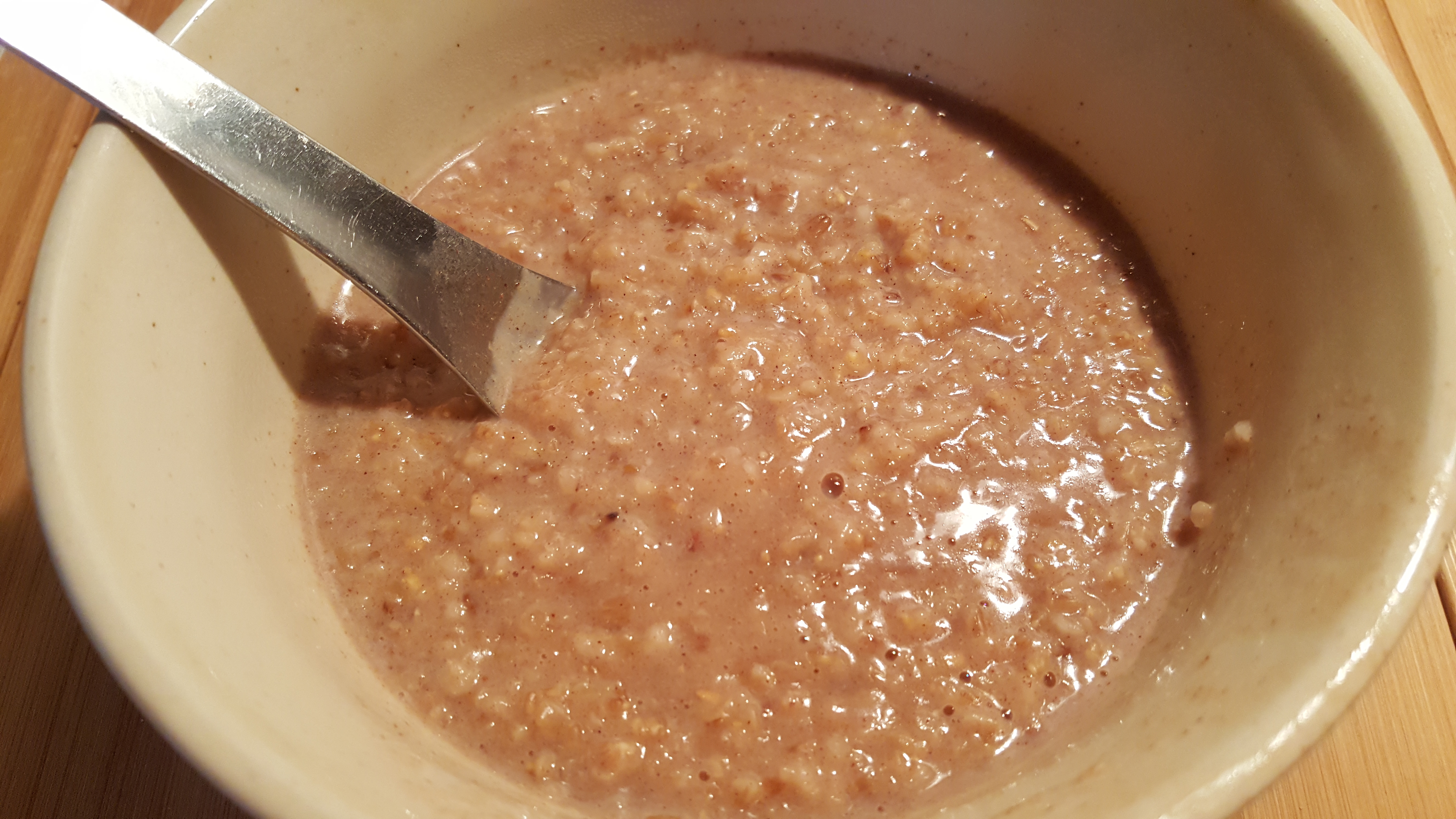 A close up of a bowl of Honey Vanilla Steel Cut Oats with a silver spoon in it
