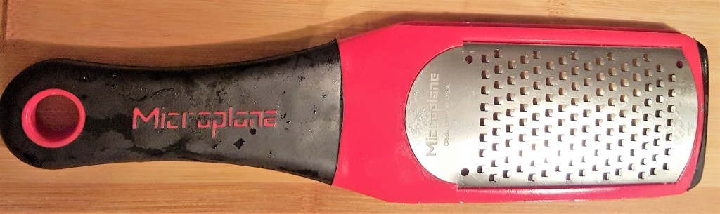 A close up of a red and black Microplane Artisan Series Coarse Cheese Grater