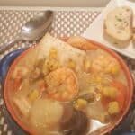 Blue bowl with shrimp, scallows, corn, green means, carrots in a creamy broth Instant Pot Seafood Corn Chowder