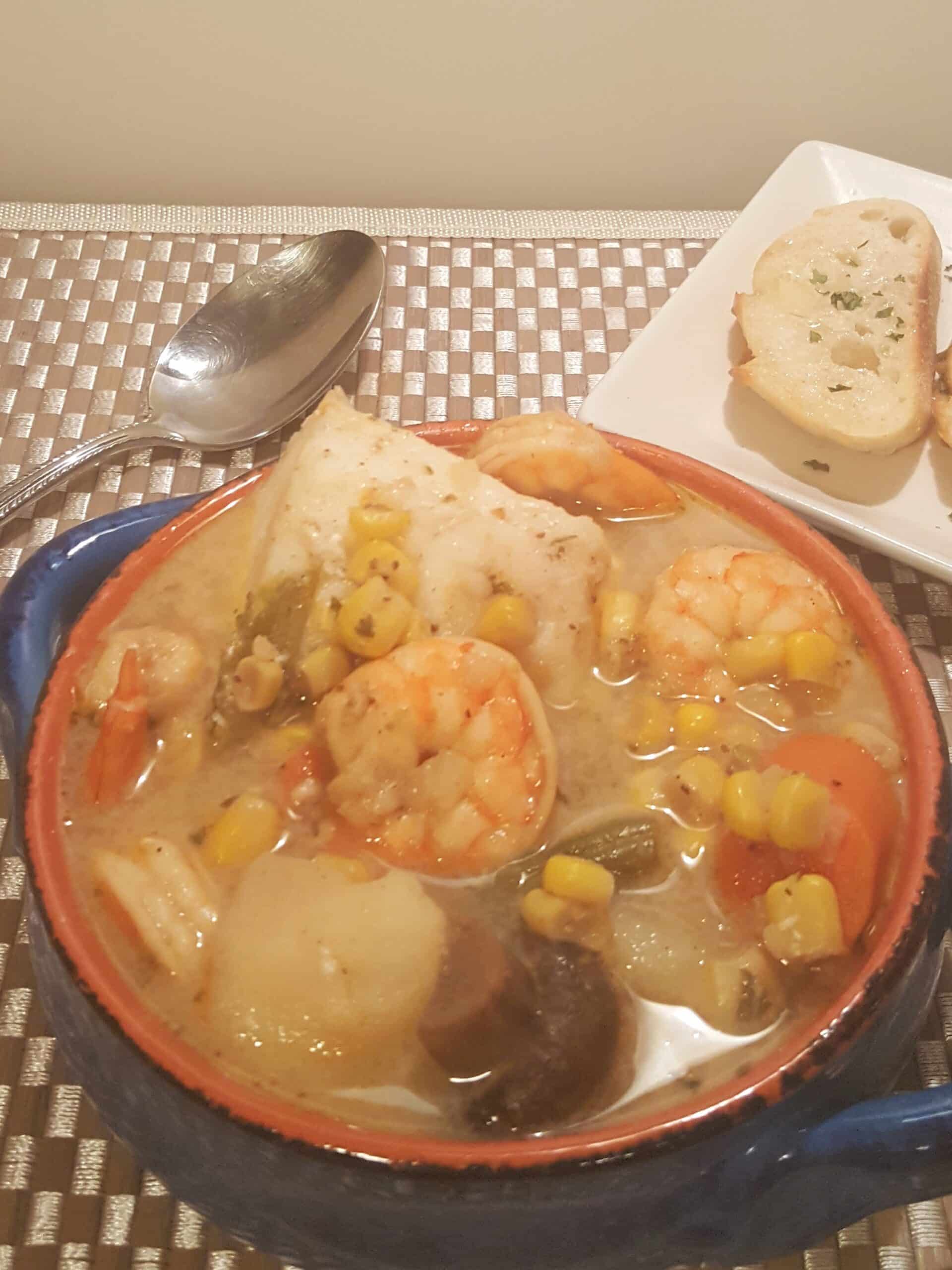 Blue bowl with shrimp, scallows, corn, green means, carrots in a creamy broth Instant Pot Seafood Corn Chowder