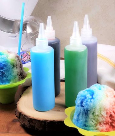 Bottles of Shaved Ice Syrup on a Wooden Plank with Two Shaved Ice Cups