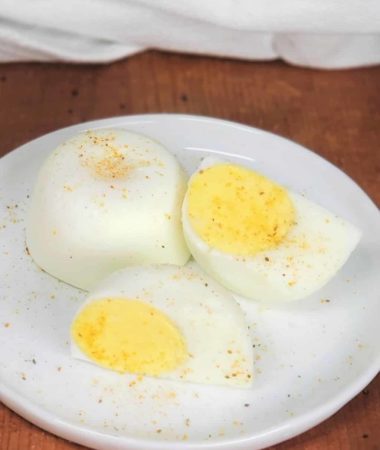 Instant Pot No Peel Hard Boiled Eggs on a while plate with one egg cut in half