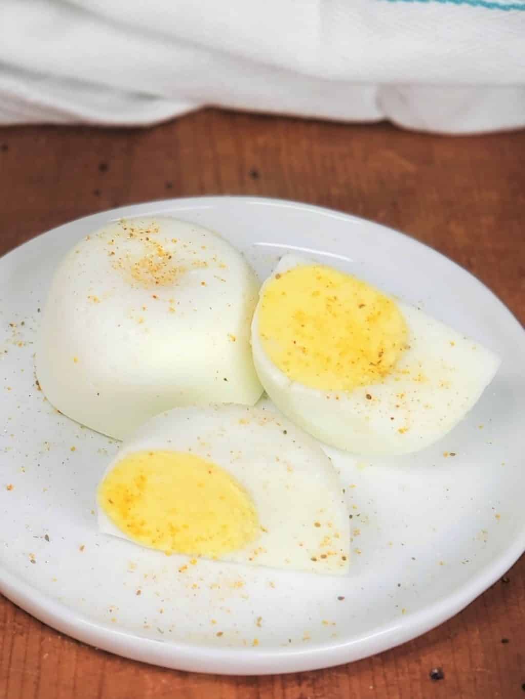 Instant Pot No Peel Hard Boiled Eggs on a while plate with one egg cut in half
