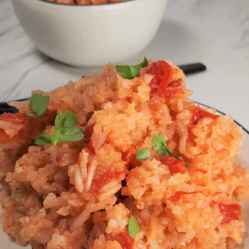 Pressure Cooker Jollof Rice on a white plate with a black fork