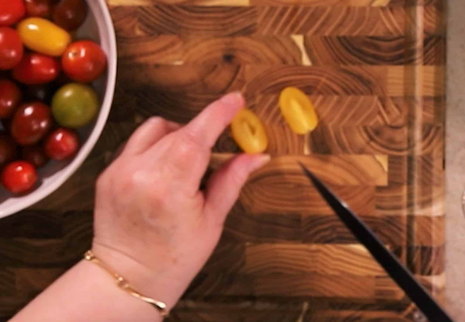 Jill slicing tomatoes horizontally on a wooden cutting board