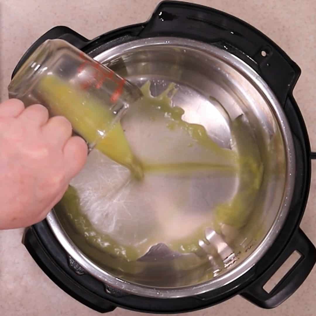 Chicken Broth in a glass measuring cup being poured into an Instant Pot